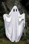 66477210-a-spooky-white-ghost-covered-by-a-sheet-with-slits-over-the-eyes-standing-in-front-of-a.jpg
