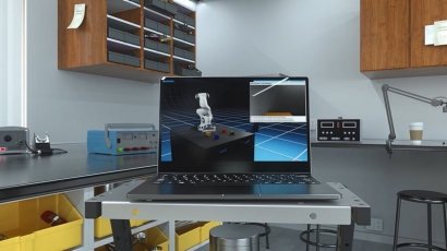 Laptop displaying 3D robotic arm design on a workshop table